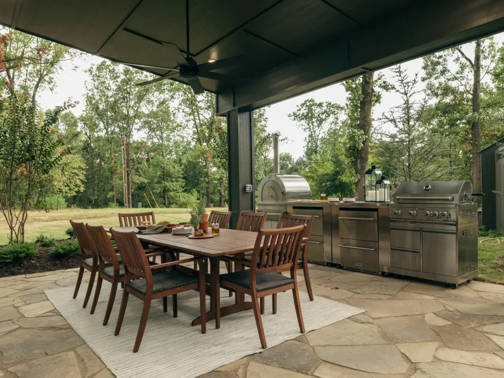 THOR Kitchen stainless steel outdoor kitchen with pizza oven and grill beside an outdoor dining table